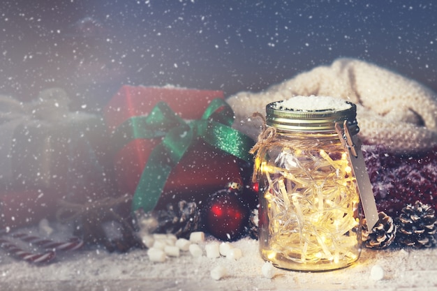 Crystal pot met lampen met een gift ernaast, terwijl het sneeuwt