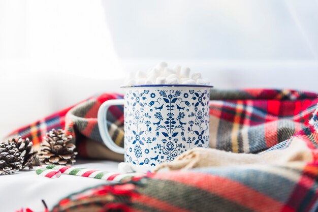 Cup met marshmallow in de buurt van sjaal en spar haken en ogen