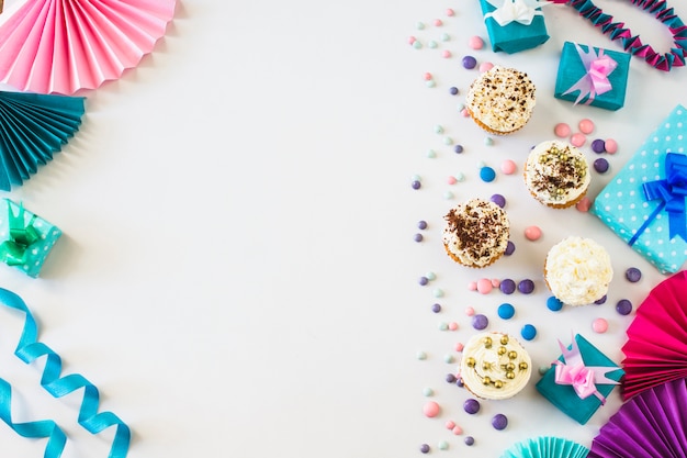 cupcakes; handfan; snoepjes; geschenkdoos en lint op witte achtergrond