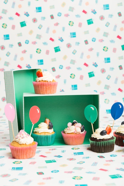 Gratis foto cupcakes met ballonbovenste laagje op lijst