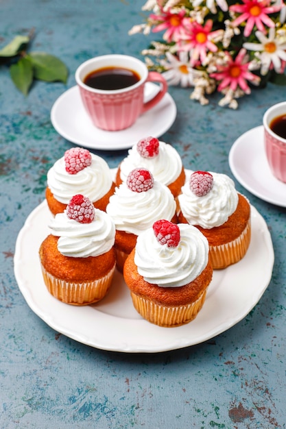 Cupcakes versierde slagroom en bevroren frambozen.