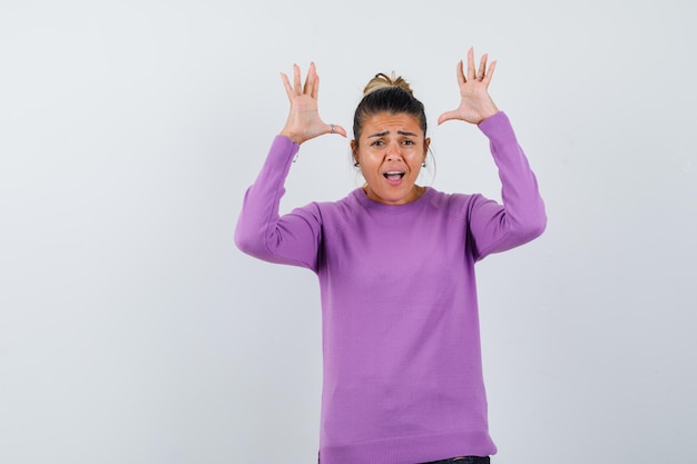 Dame die handen opsteekt in overgavegebaar in wollen blouse en gealarmeerd kijkt