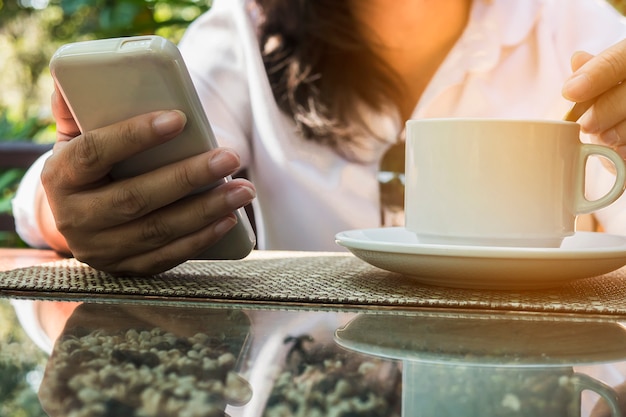 Dame die mobiele witte het drinken koffie gebruikt