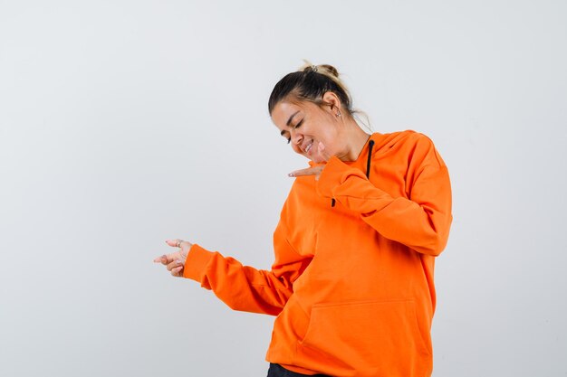 Dame die opzij wijst in oranje hoodie en er vrolijk uitziet