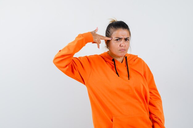 Dame die zelfmoordgebaar maakt in oranje hoodie en er serieus uitziet