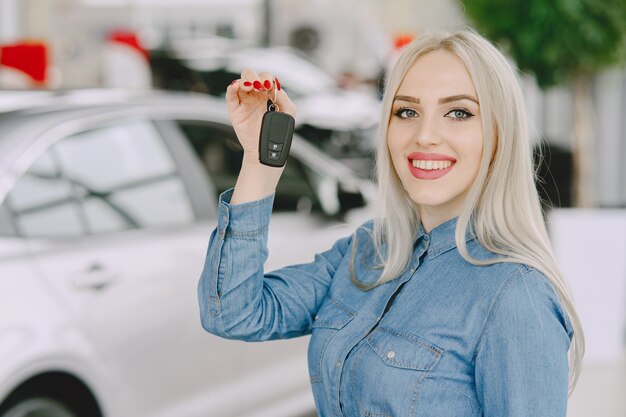 Dame in een autosalon. Vrouw die de auto koopt. Elegante vrouw in een blauwe jurk.