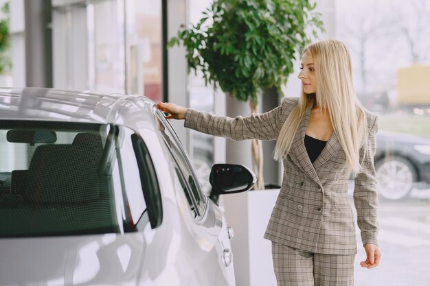 Dame in een autosalon. Vrouw die de auto koopt. Elegante vrouw in een bruin pak.