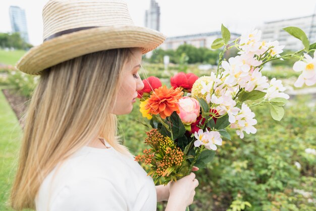 Dame in hoed met boeket bloemen in stadspark