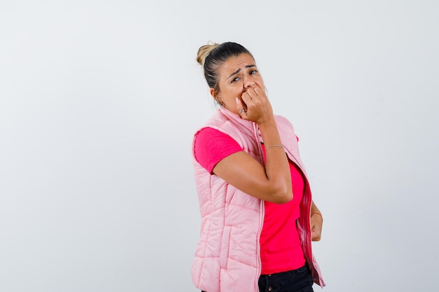 Dame in t-shirt, vest bijt in haar vuist en kijkt angstig