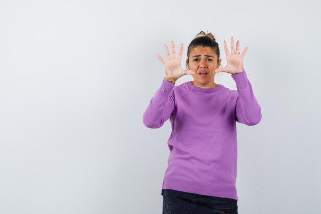 Dame in wollen blouse die een stopgebaar toont en er bang uitziet