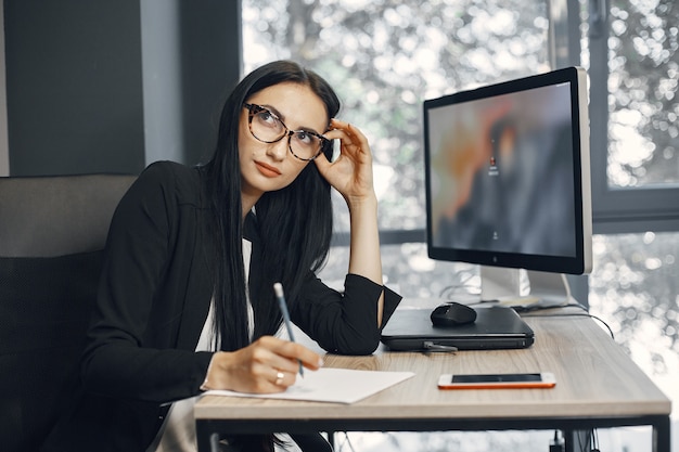 Dame met bril. Manager zit achter de computer. Zakenvrouw werkt in haar kantoor.