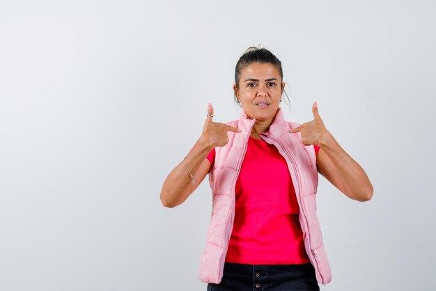 Dame wijst naar zichzelf in t-shirt, vest en ziet er zelfverzekerd uit