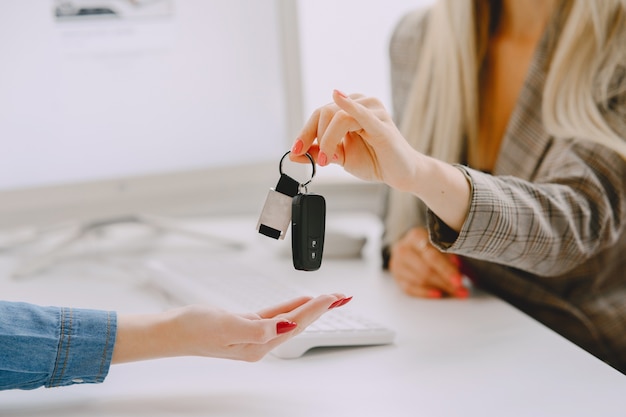 Dames in een autosalon. Vrouw die de auto koopt. Elegante vrouw in een blauwe jurk. Manager helpt de klant.