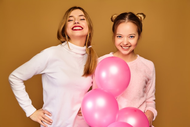Damesmodellen met roze luchtballonnen op gouden muur