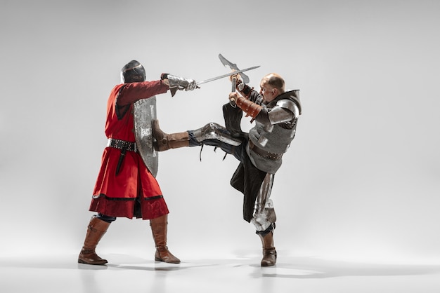 Dappere gepantserde ridders met professionele wapengevechten geïsoleerd op witte studioachtergrond.