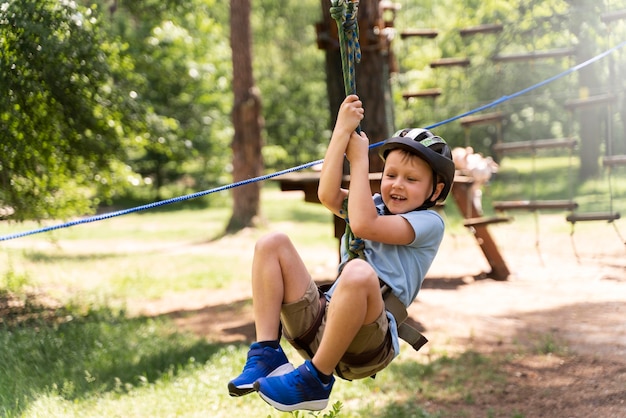 Gratis foto dappere jongen die plezier heeft in een avonturenpark