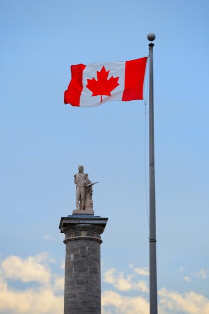 De architectuur van Montreal met standbeeld en de Nationale Vlag van Canada