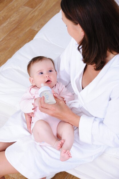 De baby wordt door zijn moeder uit de fles gevoerd