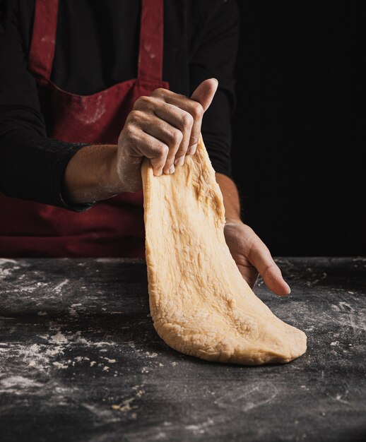 De bakker van de close-up overhandigt het kneden deegsamenstelling