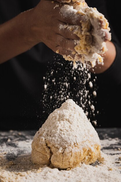 De bakkers het uitspreiden bloem van de close-up op deeg