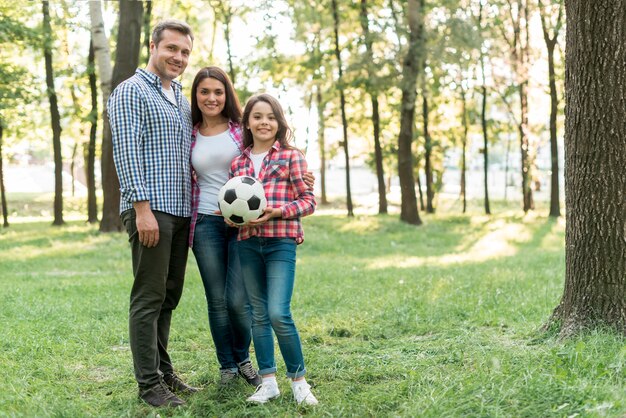 De bal van het de holdingsvoetbal van het meisje die zich met haar ouder in park bevinden