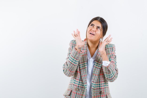 De bange vrouw steekt haar handen op een witte achtergrond