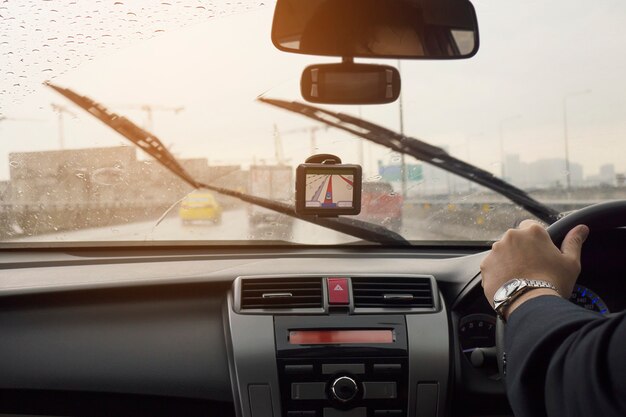 De bedrijfsmens drijft een auto in regenende dag met bewegende wisserbladen