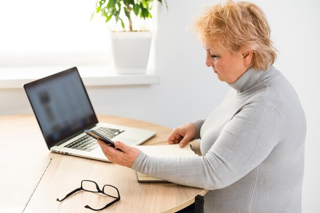 De bejaarde vrouw bij de computerlaptop.