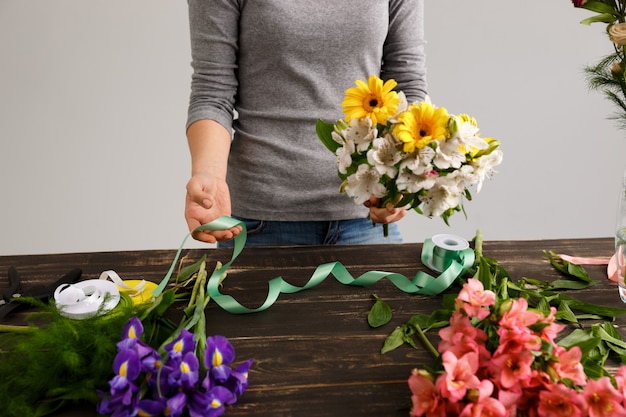De bloemistvrouw maakt boeket van kleurrijke bloemen