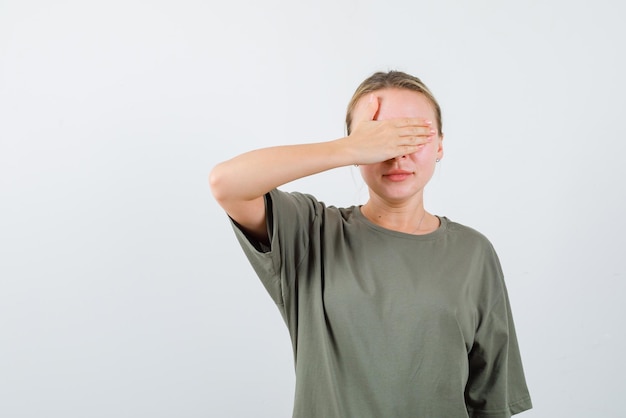 De blonde vrouw bedekt haar ogen met de hand op een witte achtergrond