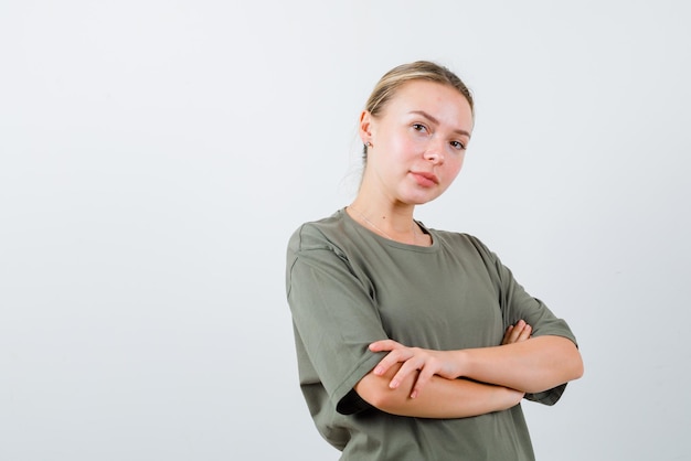 Gratis foto de blonde vrouw kijkt naar de camera door de armen over elkaar te kruisen op een witte achtergrond