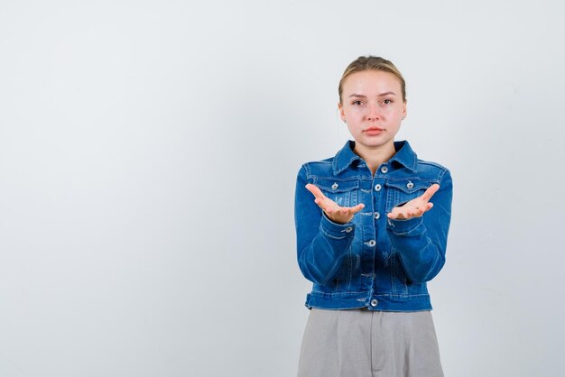 De blonde vrouw strekt haar handen uit naar de camera op een witte achtergrond