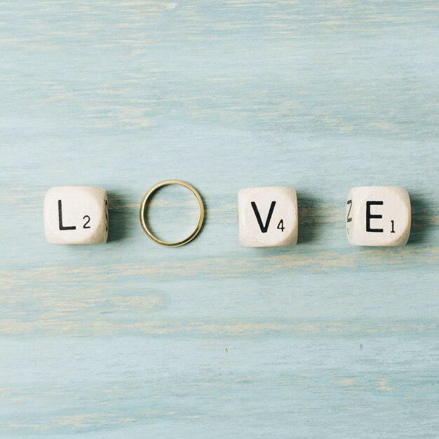 De brievenkubussen van de liefde met huwelijks gouden ring op houten textuurachtergrond