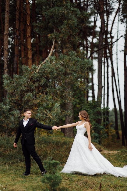 De bruid en bruidegom rennen door een bos Trouwfotoshoot
