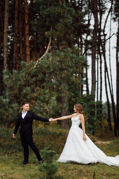 De bruid en bruidegom rennen door een bos Trouwfotoshoot