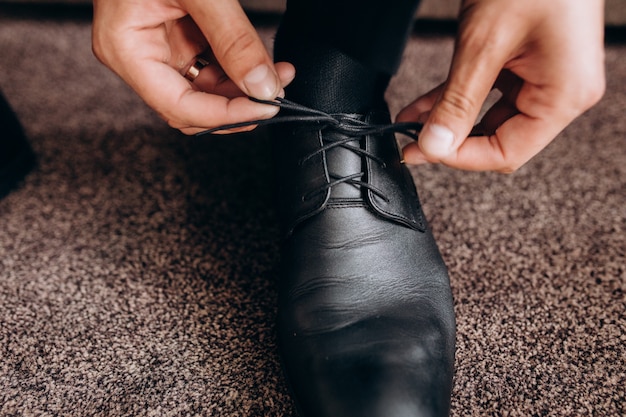 De bruidegom bindt veters op zijn schoenen zittend op een bank