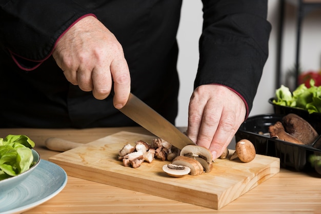 De chef-kok snijdende paddestoelen van de close-up