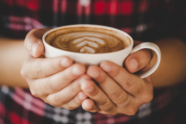 De close-uphand van wijfje die een koffiekop in de koffie houden voegt de toon van de filter retro kleur toe