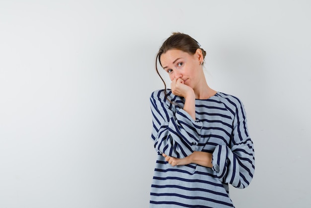 De denkende jonge vrouw zet haar vuist op de kin op een witte achtergrond