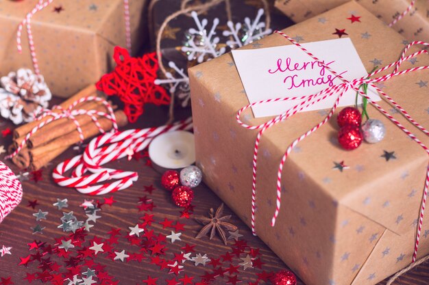 De doos van de de vakantiegift van Kerstmis met prentbriefkaar vrolijke Kerstmis op verfraaide feestelijke lijst met denneappelskaneel