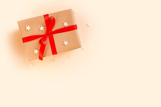 De doos van de gift van kerstmis met rode strik op beige achtergrond. vakantieconcept, nieuwjaarscadeautjes. hoge kwaliteit foto