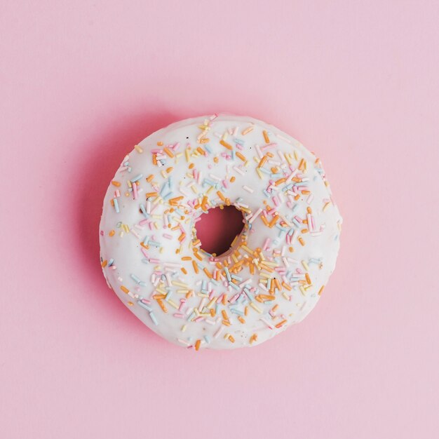 De doughnut met bovenste laag bestrooit op roze achtergrond