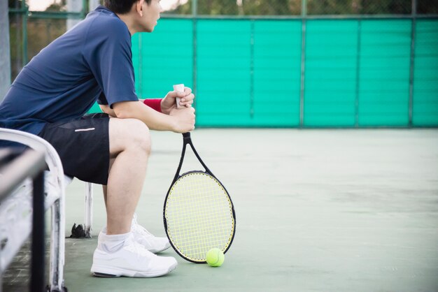 De droevige tennisspeler die in het hof zit na verliest een gelijke