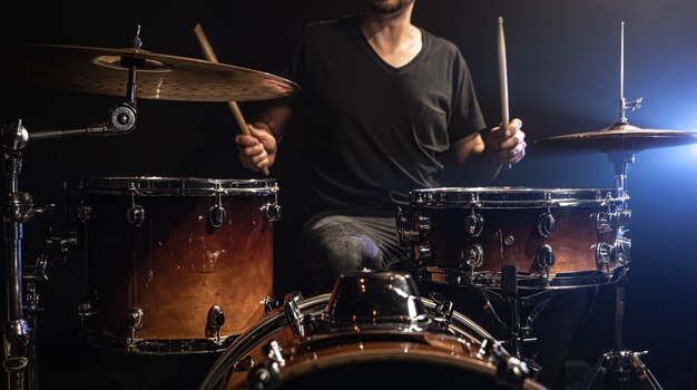 De drummer speelt drums terwijl hij aan het drumstel op het podium zit