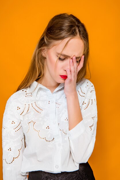 De ernstige gefrustreerd jonge mooie zakenvrouw op oranje achtergrond