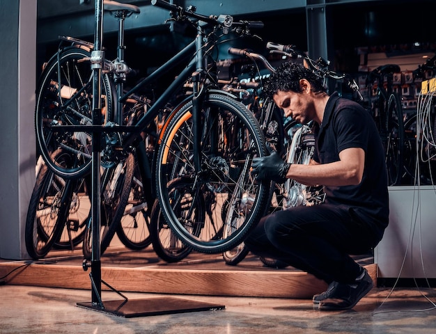 De ervaren jonge meester repareert de fiets van de klant op de werkplek.