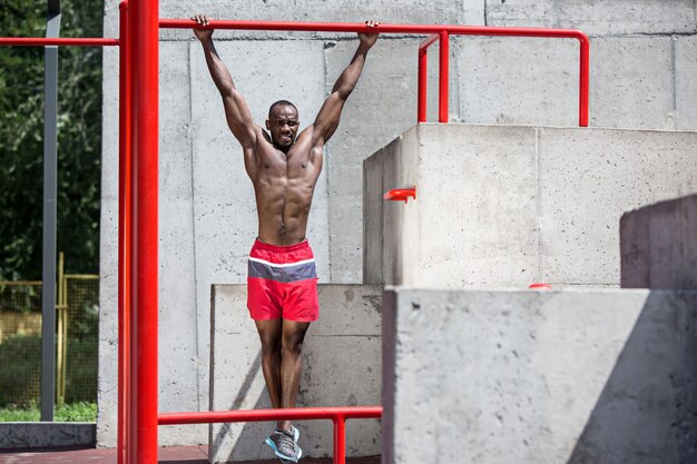 De fitte atleet die oefeningen doet. Afro of Afro-Amerikaanse man buiten in de stad. Trek sportoefeningen uit.