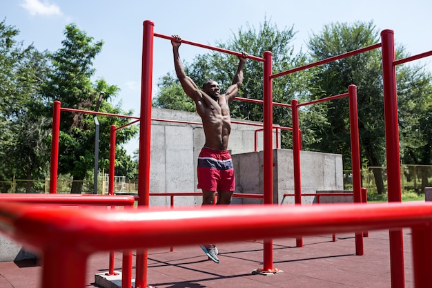 De fitte atleet doet oefeningen in het stadion. Afro of Afro-Amerikaanse man buiten in de stad. Trek sportoefeningen uit. fitness, gezondheid, lifestyle concept