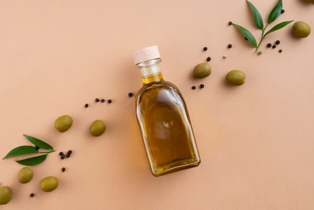 De fles van de olijvenolie met gespreide olijven en bladeren daarna