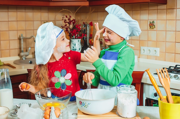 Gratis foto de gelukkige familie grappige jonge geitjes bereiden deeg voor, bakken koekjes in keuken